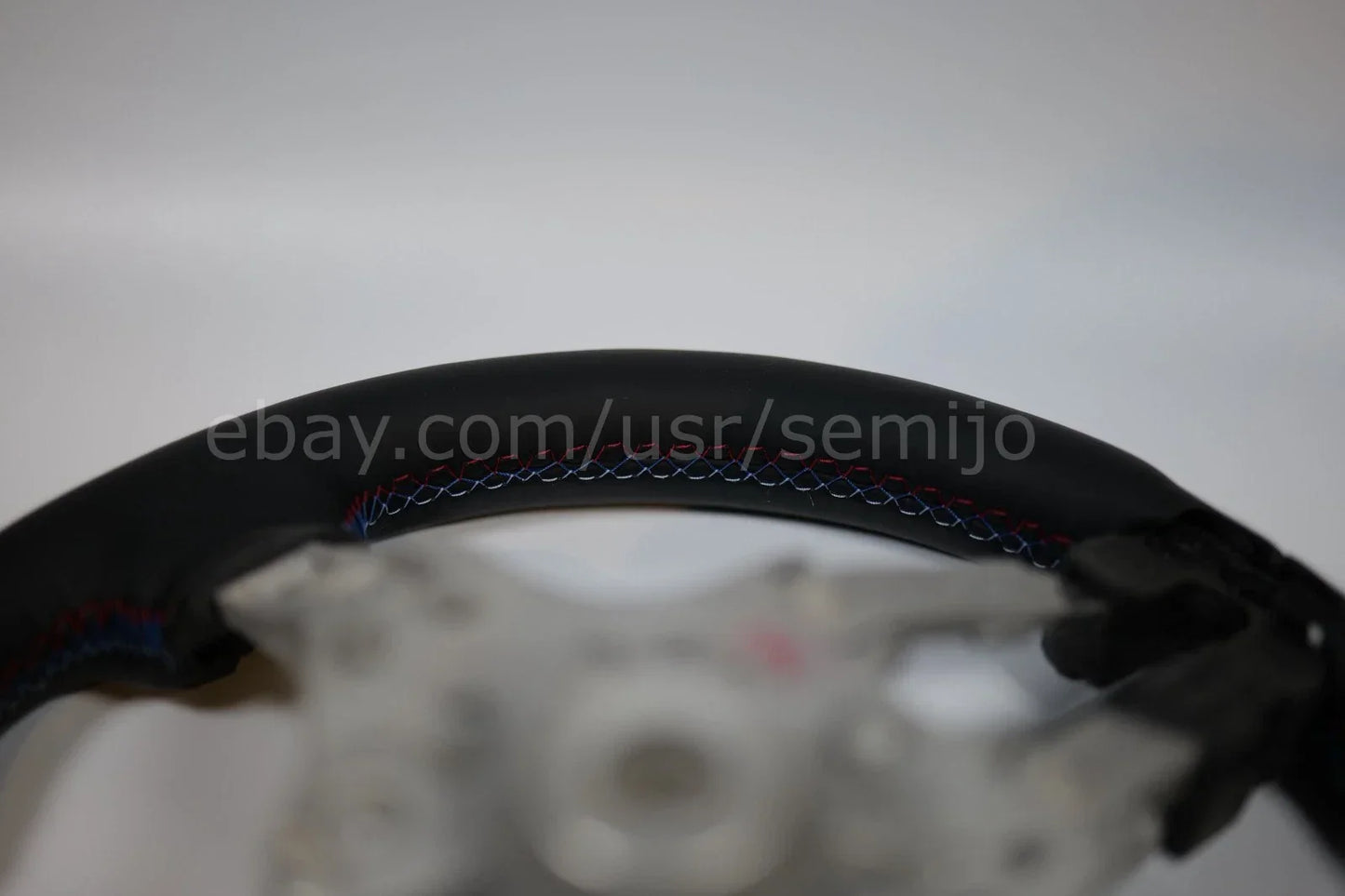 BMW F Series steering wheel closeup with tricolor stitching on black leather