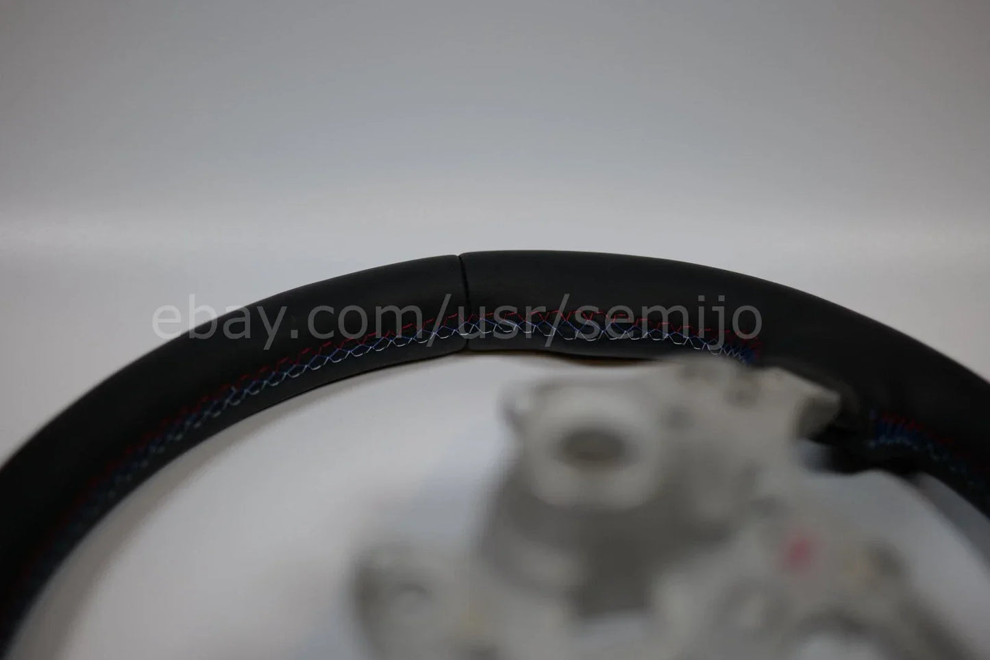 BMW F Series black leather steering wheel with tri-color stitching, close-up view
