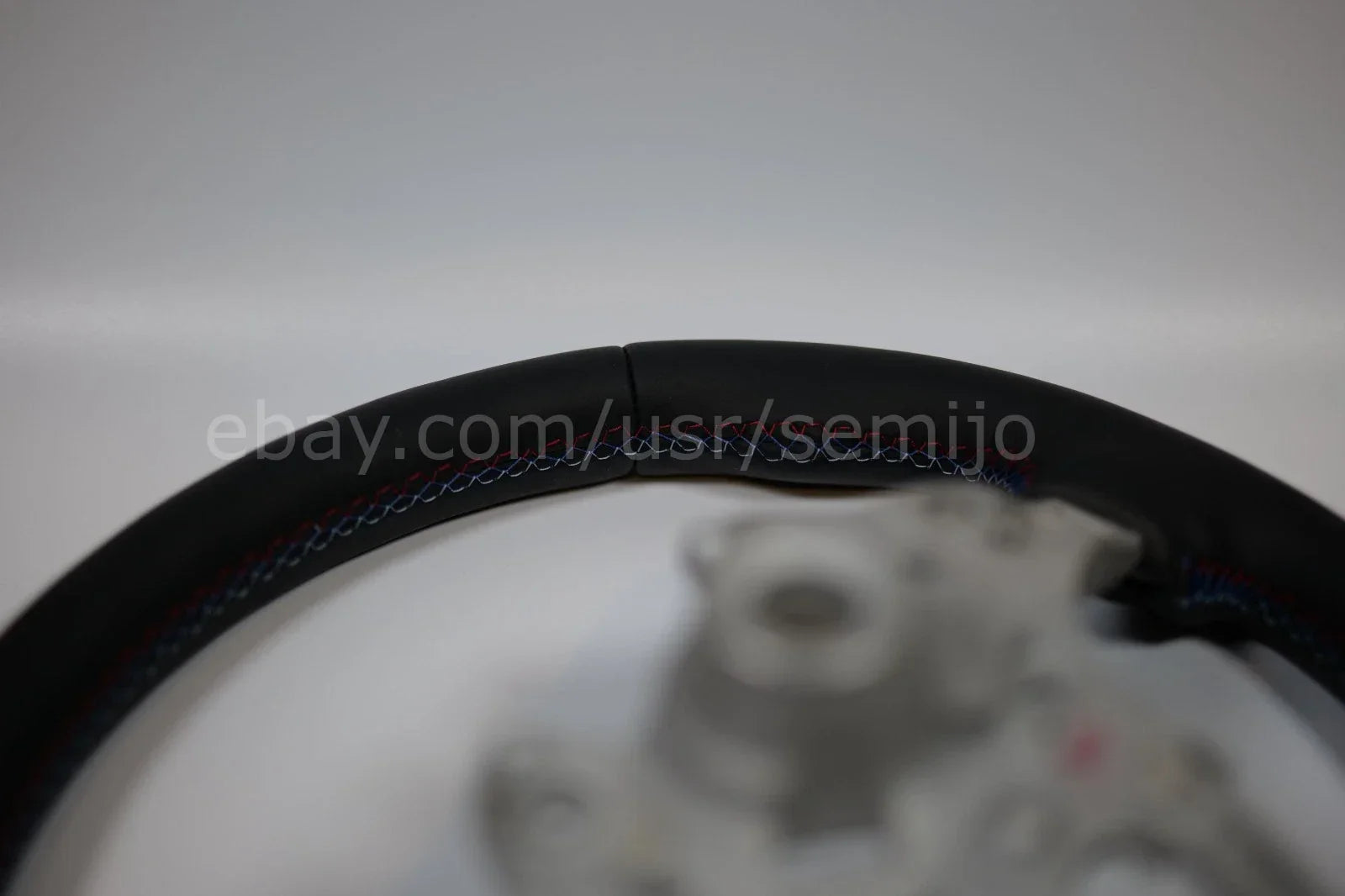 BMW F Series black leather steering wheel with tri-color stitching, close-up view