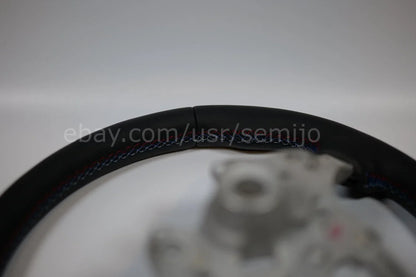 BMW F Series black leather steering wheel with tri-color stitching, close-up view