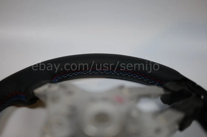 BMW F Series steering wheel closeup with tricolor stitching on black leather