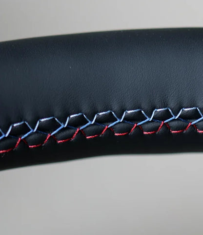Close-up of black leather BMW F Series steering wheel with tri-color stitching detail