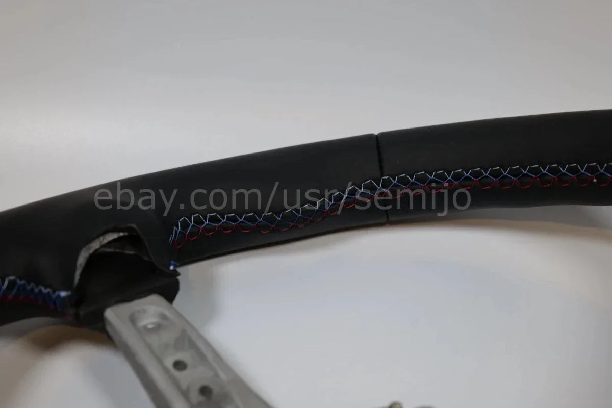 Close-up of BMW F Series M Sport steering wheel with tricolor stitching detail