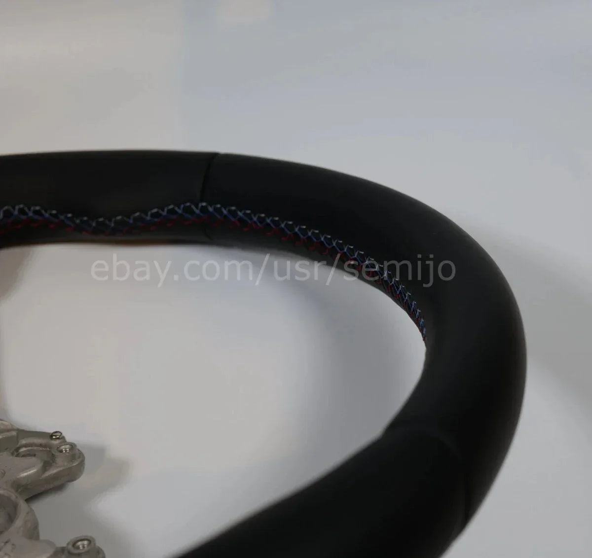 Close-up of BMW F Series M Sport steering wheel with tri-color stitching detail
