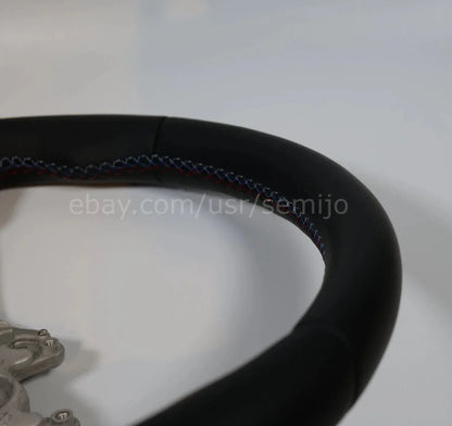 Close-up of BMW F Series M Sport steering wheel with tri-color stitching detail