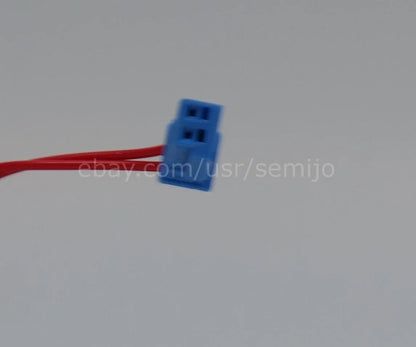 Close-up of a blue automotive electrical connector with red wires against a plain background